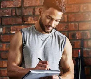 Personal trainer anotando dados em uma prancheta.